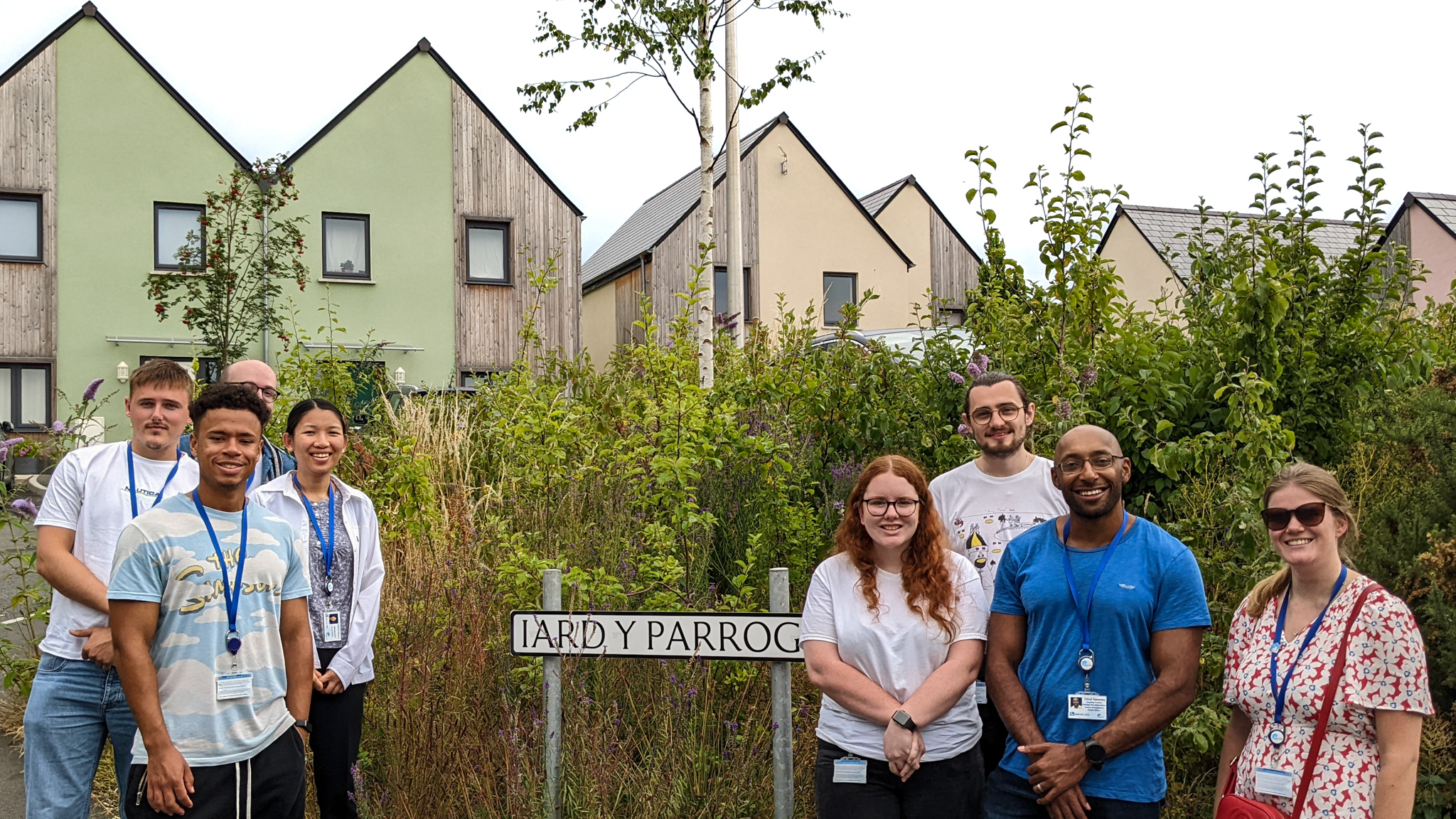 Trainees stand next to street sign of Wales & West Housing properties at Iard Y Parrog