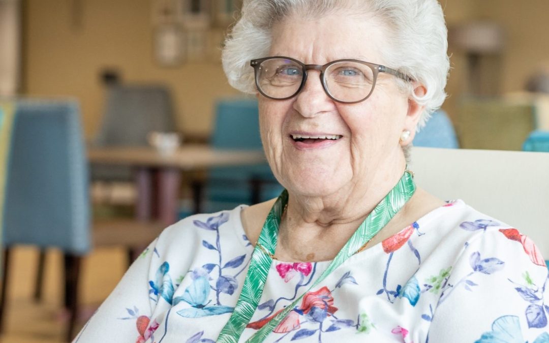 Elderly WWH resident smiling sat in dining room at extra care scheme