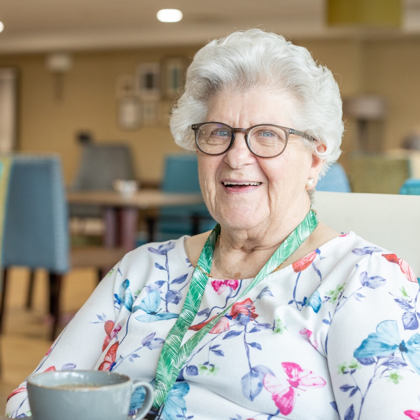 Elderly WWH resident smiling sat in dining room at extra care scheme