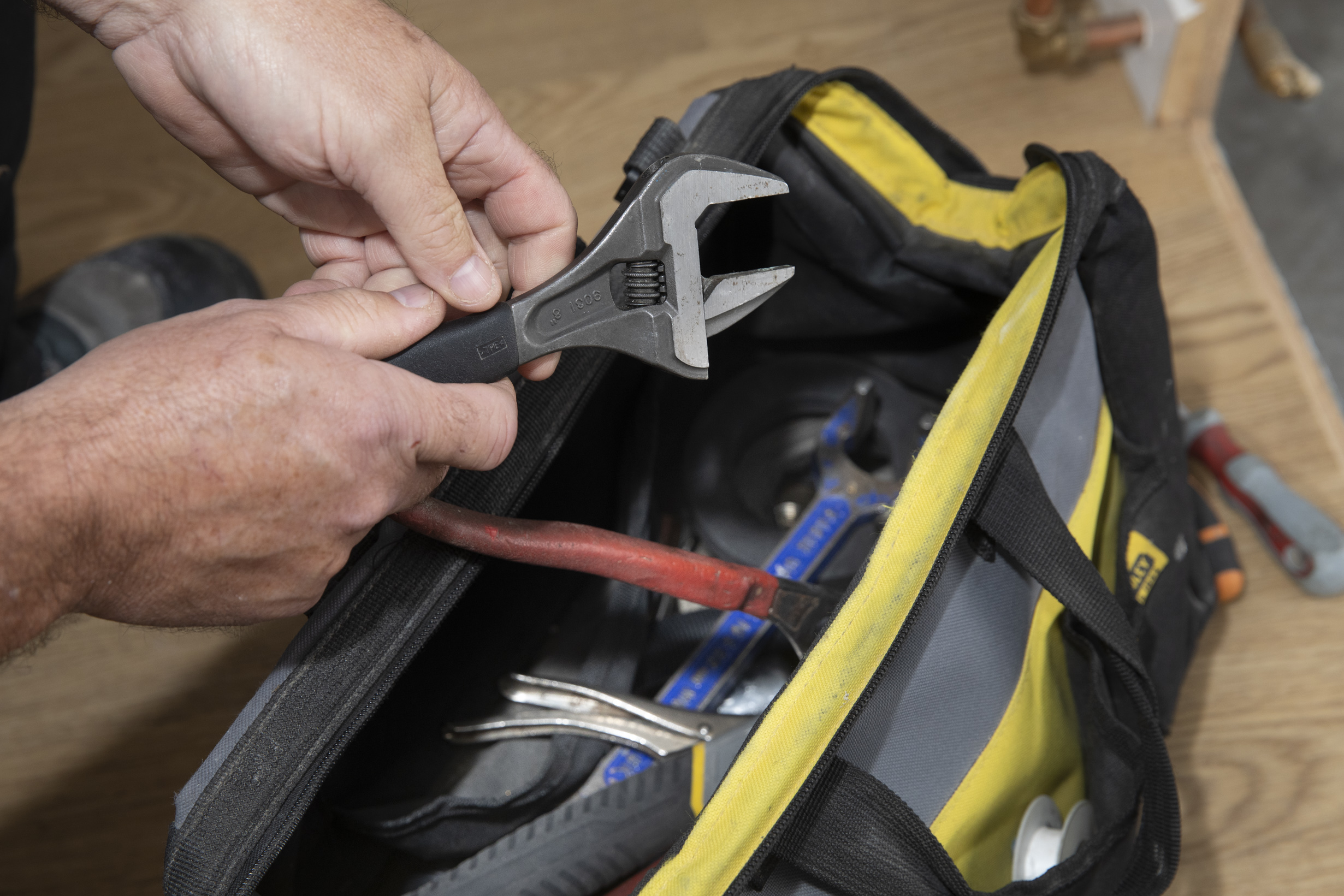 Persons hands taking adjustable wrench out of toolbox