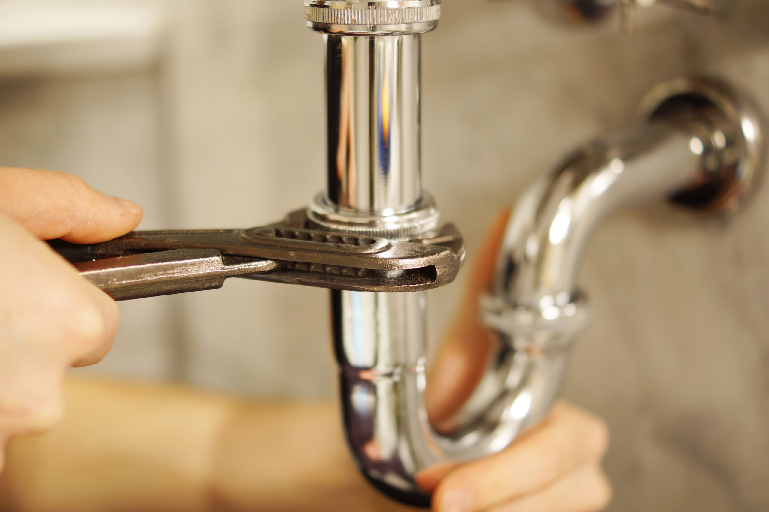 Person repairing pipes using wrench