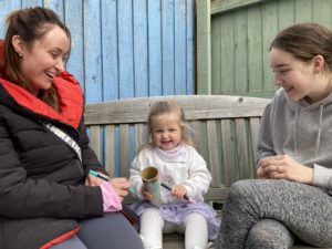 Child sitting on a bench with two adults