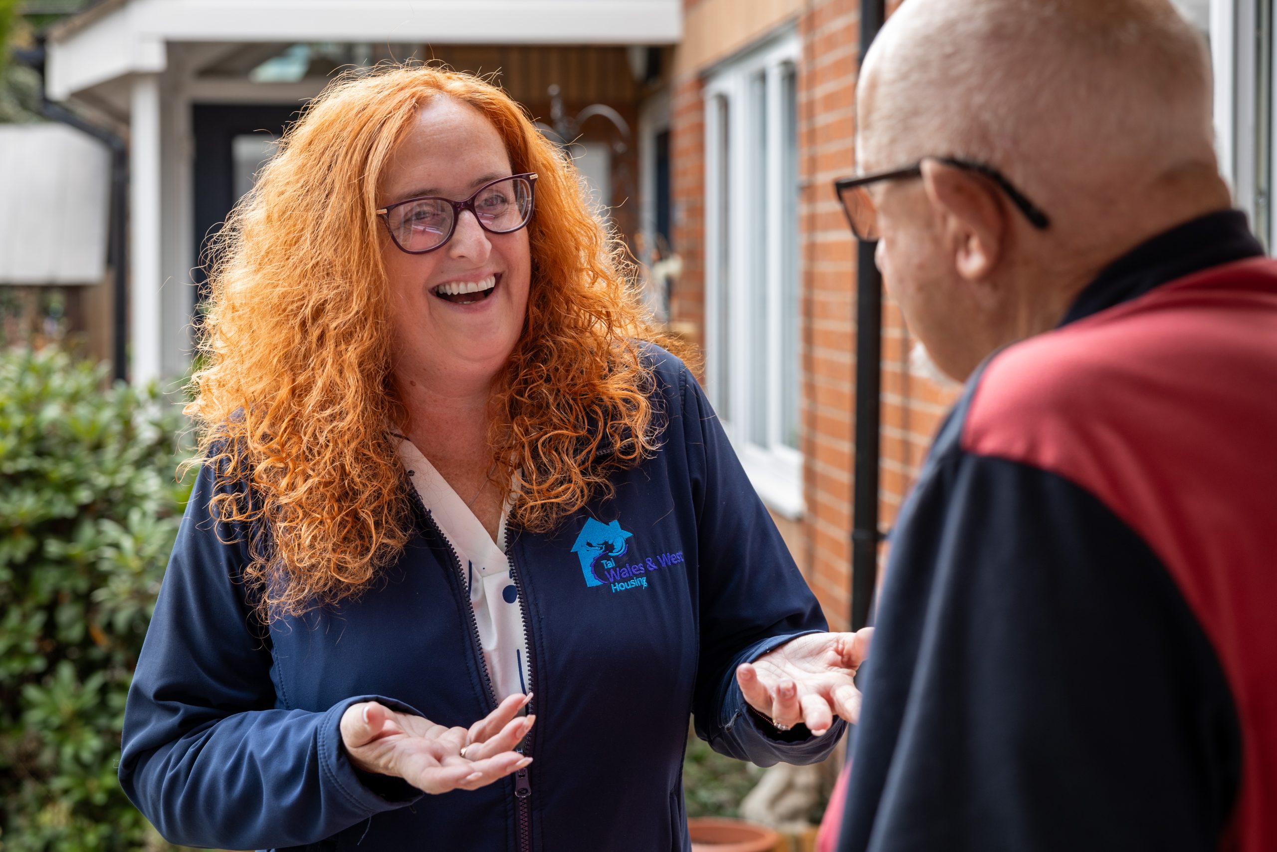 WWH Housing Officer in front of three properties smiling to camera